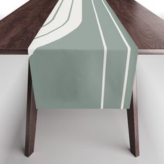 a table with a green and white striped runner on it's edge, next to a brown wooden table