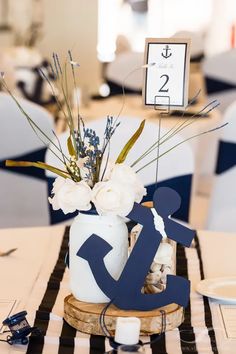 there is a vase with flowers and an anchor on the table at this wedding reception