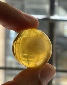 a hand holding a yellow glass object in front of a window with lots of windows behind it