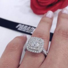 a woman's hand with a ring on it and a rose in the background