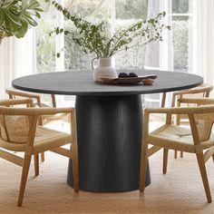 a round table with chairs around it in front of a window and potted plant