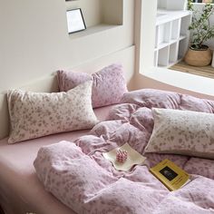 a bed with pink comforter and pillows on it