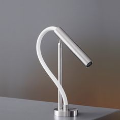 a modern desk lamp on top of a metal box with a white cord attached to it