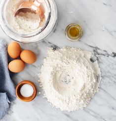 flour, eggs and other ingredients on a marble counter top