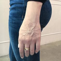 a woman's hand with a spider tattoo on her left wrist and the other arm