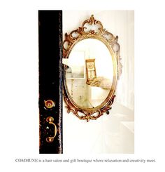 a mirror hanging on the side of a white wall next to a black and gold door