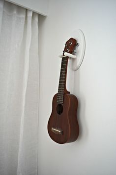 a ukulele hanging on the wall next to a curtain