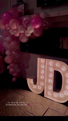 the letter j is lit up in front of balloons that spell out the word dj