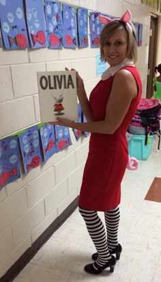 a woman in a red dress holding up a book