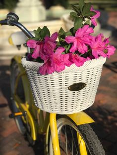 pink flowers in a basket on the back of a yellow bicycle with white handlebars