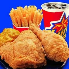 fried chicken and french fries are on a plate with two cups of soda in the background