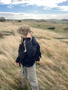 a woman standing in a field talking on her cell phone