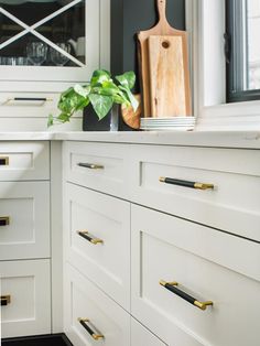 a kitchen with white cabinets and gold pulls on the handles, along with a cutting board