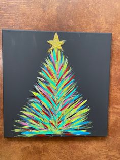 a colorful christmas tree painted on a black canvas with gold star in the top corner