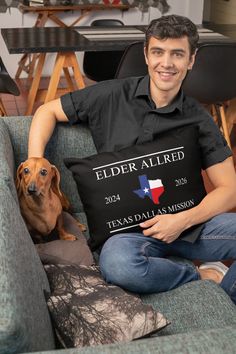 a man sitting on a couch holding a pillow with a dog laying next to him