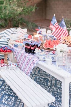 an outdoor picnic table with american flags and watermelon sandwiches on it for patriotic day