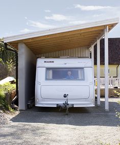 a white motor home parked in front of a building with a man looking out the window