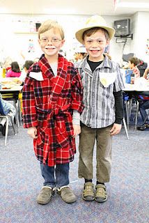 two young boys standing next to each other in front of a classroom full of desks