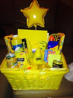 a yellow basket filled with various items on top of a table next to a star shaped balloon