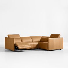 a brown leather sectional sofa sitting on top of a white floor next to a wall