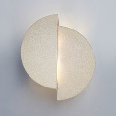 a white wall mounted light with a leaf shaped design on it's back side