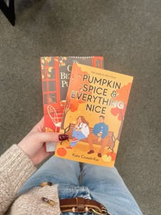 a person is holding two books in their hands while they are sitting on the floor