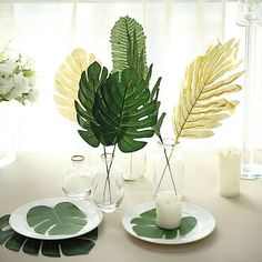 the table is set with plates and vases filled with flowers, leaves and candles