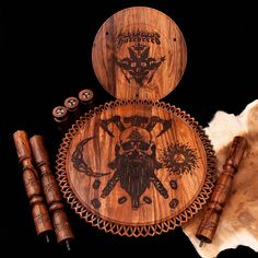 two wooden plates with designs on them next to some candles and other items in front of a black background