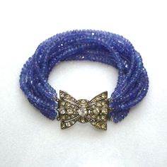 "A collection of very fine quality gemstones, these are sparkling tanzanite micro faceted gems with glittery shine and beautiful drape. The impressive nine strands are highlighted by a gorgeous vintage rhinestone box clasp to dress the inner or outer wrist and secures at 7.25\" long. When worn the strands all lay obediently side by side, not clustered as in the photos. The sparkle and flash that comes off of this tanzanite is glorious and utterly glamorous and this bracelet is sure to become a f Elegant Sapphire Bracelets With Faceted Beads, Elegant Sapphire Bracelet With Faceted Beads, Elegant Blue Multi-strand Bracelets, Elegant Tanzanite Jewelry With Faceted Beads, Tanzanite Bracelet, Faceted Gems, Silver Rhinestone, Statement Bracelet, Vintage Rhinestone