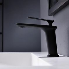 a black faucet sitting on top of a white sink next to a mirror