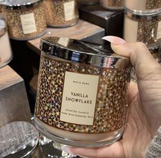 a person holding up a candle in front of many other candles on display at a store