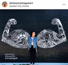 a woman standing in front of a wall with a mural on it