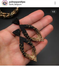 a hand holding three pieces of black and gold beaded jewelry in it's palm