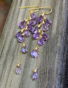 These uniquely shaped tumble drop amethyst stones are bright and clear. They swing around and reflect light in an eye catching way. They measure 3.125" from the top of the ear wire. Wrapped in gold filled wire. Purple Dangle Teardrop Earrings With Ear Wire, Gold Long Drop Chandelier Earrings With Gemstones, Elegant Gold Chandelier Earrings With Amethyst, Elegant Gold Amethyst Chandelier Earrings, Amethyst Drop Jewelry In Yellow Gold, Purple Wire Wrapped Chandelier Drop Earrings, Purple Wire Wrapped Long Drop Jewelry, Wire Wrapped Amethyst Drop Earrings, Lavender Teardrop Jewelry With Ear Wire