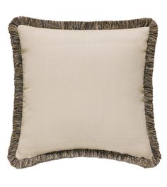 a beige pillow with fringe trim