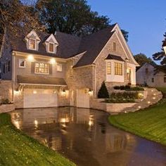 a house that is lit up at night with lights on the front and side of it