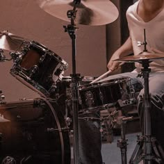 a man sitting behind a drum set on top of a wooden floor next to a wall