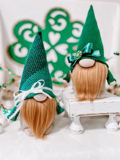 two green gnome hats sitting on top of a white bench