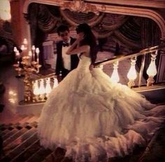 a bride and groom are standing on the stairs in front of a chandelier