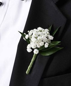 a boutonniere with white flowers on the lapel of a man in a tuxedo