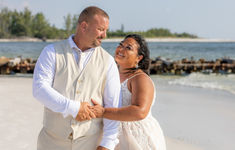 a man and woman are standing on the beach holding each other's hands as they dance