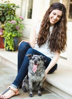 a woman sitting on the steps with her dog