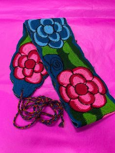 two pieces of fabric with flowers on them sitting on a pink cloth covered tablecloth