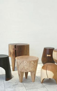 several wooden stools sitting on top of a white tiled floor next to each other