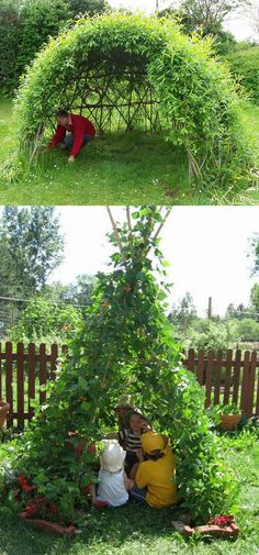 two people and a child are sitting in the grass near a small house made out of plants