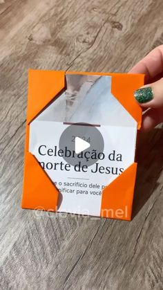 a person holding an orange and white origami box on top of a wooden table