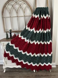 a red and green blanket sitting on top of a wooden chair