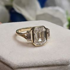 an engagement ring with three baguets on top of it, sitting on a cushion