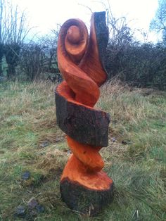 a wooden sculpture sitting on top of a lush green field