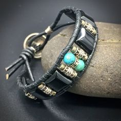 "Mens Turquoise and Onyx beaded leather wrap bracelet in sterling silver with a a dash of Pyrite finished off with a genuine Indian-head Nickel button clasp. Handmade in my home studio in Austin, Texas, U.S.A. I love designing mens jewelry! I always imagine what kind of man will wear it. This bracelet is made of turquoise, onyx, pyrite and sterling silver. The button clasp is made of genuine Indian-head nickel and comes in an Indian Head or Buffalo Head faced The style combines a modern, masculi Adjustable Masculine Silver Jewelry, Masculine Adjustable Silver Jewelry, Adjustable Leather Bracelets With Natural Stones, Hand Wrapped Leather Jewelry With Round Beads, Bohemian Hand Wrapped Beaded Bracelets, Artisan Hand Wrapped Black Bracelets, Artisan Hand Wrapped Black Bracelet, Artisan Hand-wrapped Black Bracelet, Bohemian Black Leather Bracelet With Round Beads